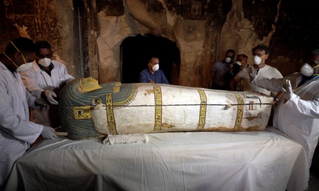 Archaeologists removing the cover of the ancient Egyptian sarcophagus. They use small pieces of wood